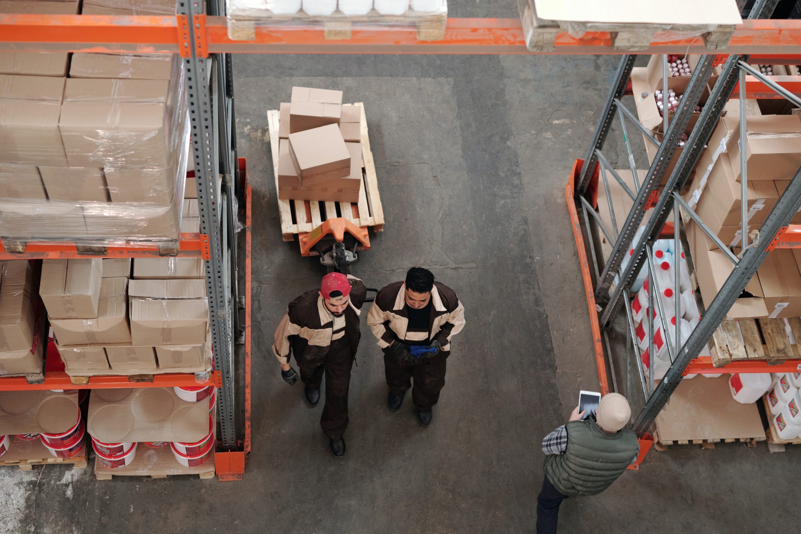 employees moving packages in warehouse, surrounded by shelves filled with boxes