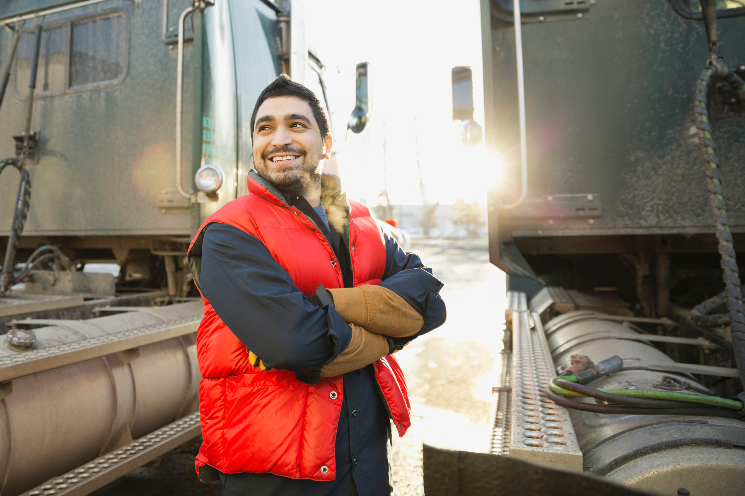 Confident worker standing by semi trucks outdoors